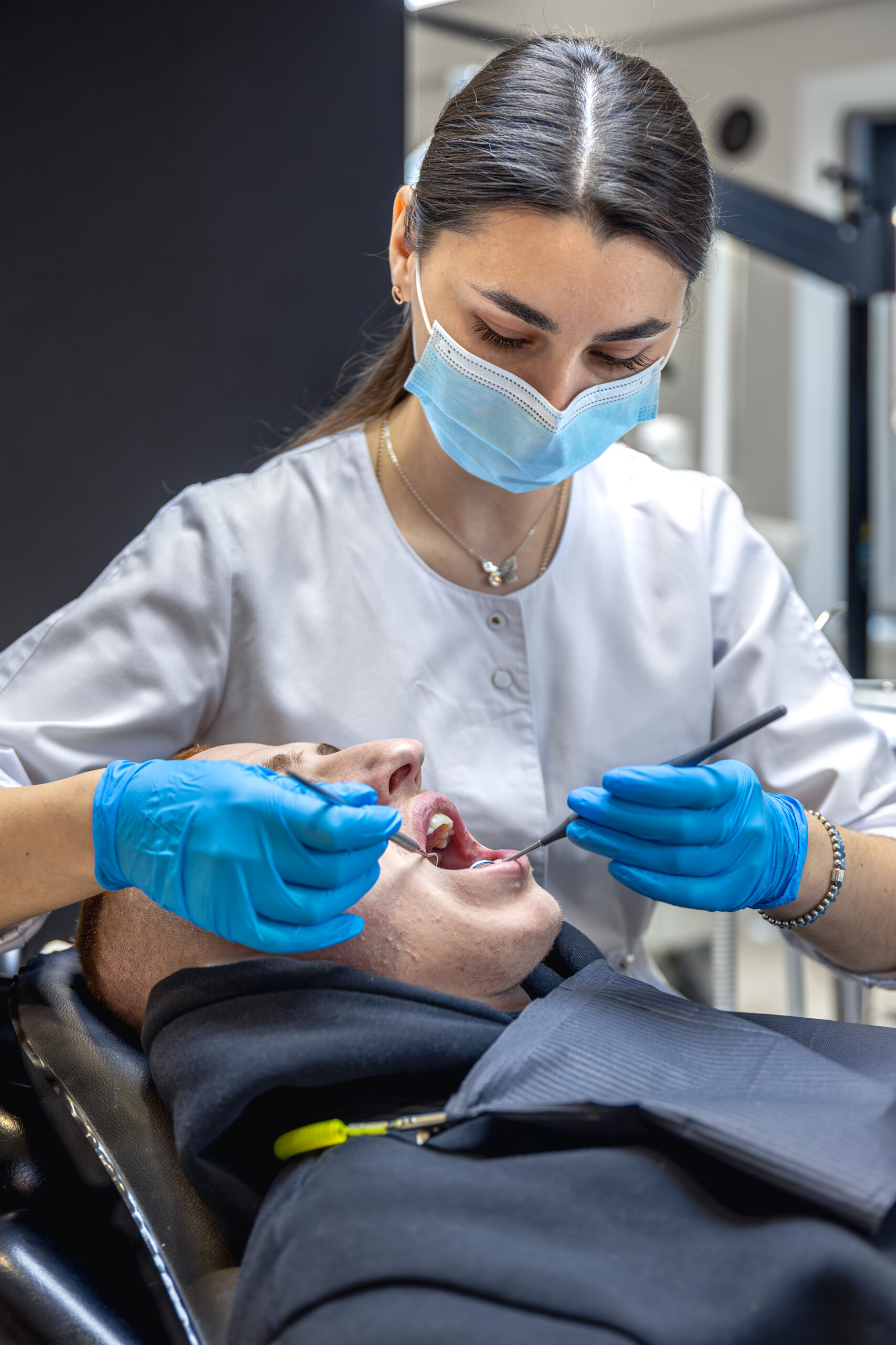Female dentist treats patient's teeth. Stomatologist working with professional equipment.